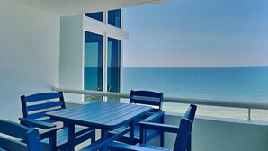 Een balkon met een tafel en stoelen, met uitzicht op een waterpartij.