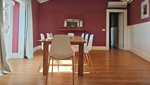 Ein Essbereich mit einem Holztisch, weißen Stühlen, einer Decke mit Einbaustrahlern und einer roten Wand.
