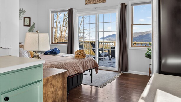 Une chambre avec un lit, un bureau et une vue sur une terrasse et des montagnes.