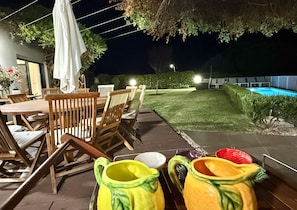 Une terrasse extérieure avec des meubles en bois, une piscine et une pelouse bien entretenue.
