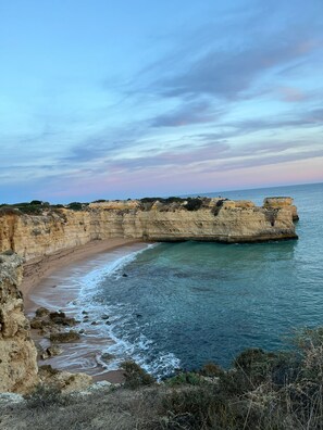 Un paysage côtier avec des falaises, une plage de sable et la mer.