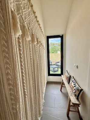 A hallway with a macramé curtain, a bench with decorative pillows, and a view of an outdoor seating area through a door. - Vila Algarvve II-5 mn walking from Beach-heated pool-see view-16 pax (Albufeira)
