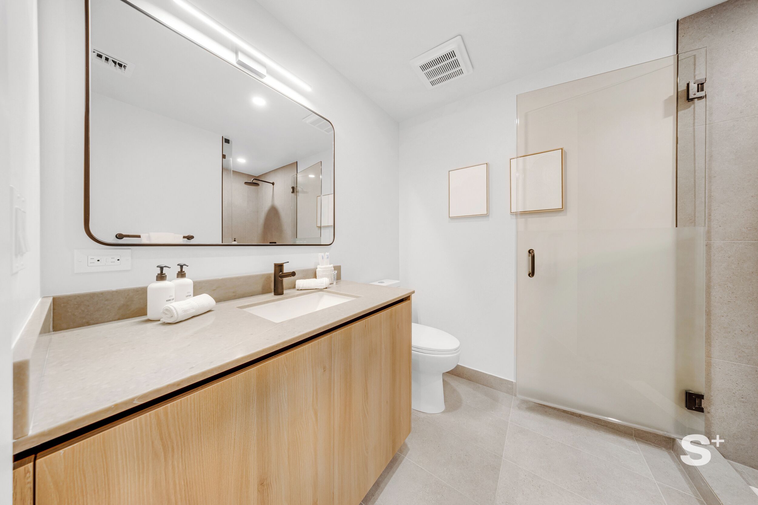 Un bagno moderno con uno specchio grande, un lavandino e un water.