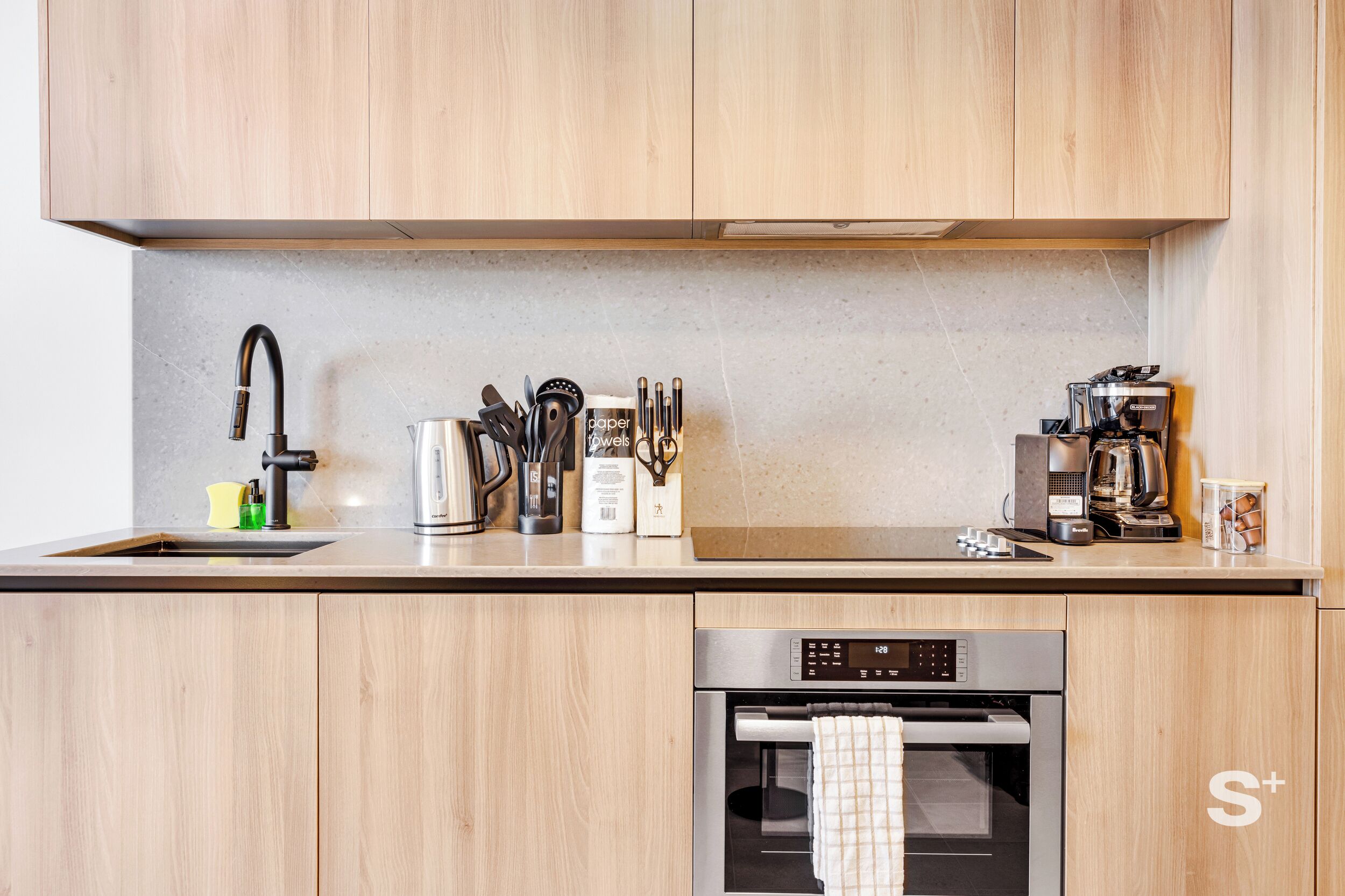 Een moderne keuken met houten kastjes, roestvrijstalen apparatuur en een inbouwoven.