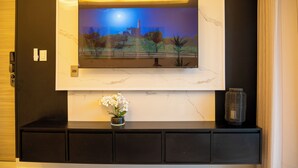 A flat-screen TV mounted on a wall with a night scene. Below the TV, there is a black console with a small potted plant. - Fabulous apartment in the center of jarabacoa rep dom. (Jarabacoa)