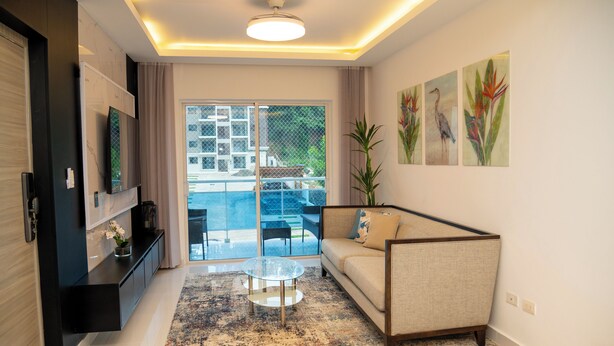 A modern living room with a sofa, a glass coffee table, and artwork on the wall. - Fabulous apartment in the center of jarabacoa rep dom. (Jarabacoa)