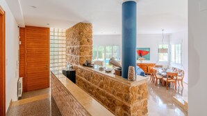 A modern kitchen with a stone island, wooden cabinets, and a dining area with a table and chairs.