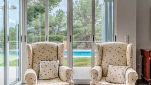 A room with two armchairs facing a sliding glass door leading to a pool area.