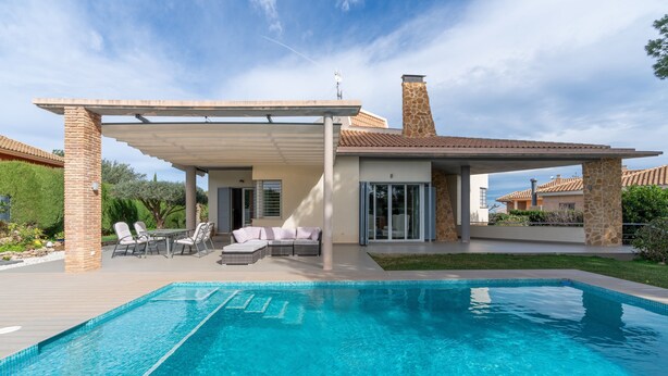 A modern house with a swimming pool, outdoor seating, and a covered patio.