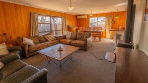 A cozy living room with a sectional sofa, a coffee table, and a dining area with a table and chairs. - Timber & Stars Cabin - your cosy getaway in the heart of Twizel. (Twizel)