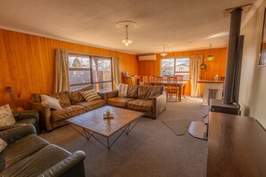 A cozy living room with a sectional sofa, a coffee table, and a dining area with a table and chairs. - Timber & Stars Cabin - your cosy getaway in the heart of Twizel. (Twizel)