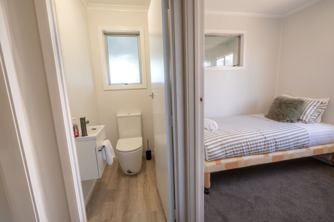 A compact room with a bed, a small window, a toilet, and a sink.