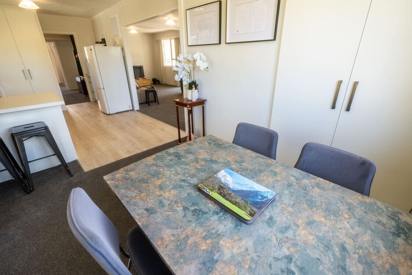 A dining area with a table, chairs, and a refrigerator in the background.