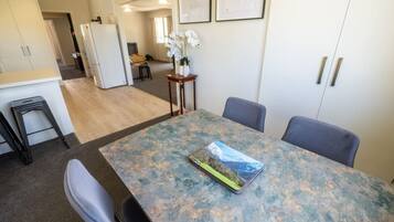 A dining area with a table, chairs, and a refrigerator in the background.