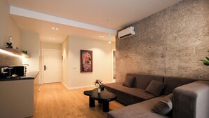 A modern living room with a brown sofa, a coffee table, and a kitchen area with a microwave. - One Bedroom Apartment with City and Mountain View (Tiranë)
