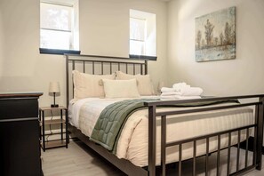 Un dormitorio con cama, mesitas de noche y un cuadro en la pared.