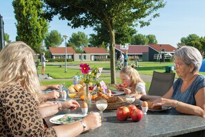 A group of people dining outdoors at a table with food and drinks. - Zeeland:10 minutes by bike from the Sudwesten sea to a cozy vacation park (Koudekerke)
