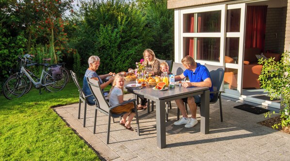 A family dining outdoors with a table set for breakfast. - Zeeland:10 minutes by bike from the Sudwesten sea to a cozy vacation park (Koudekerke)