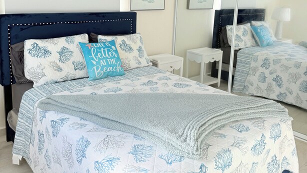 A bedroom with a bed, a ceiling fan, a mirror, and artwork on the wall. - Sun Beach Escape – Vacation Rental in Boquerón, Cabo Rojo (Boquerón)