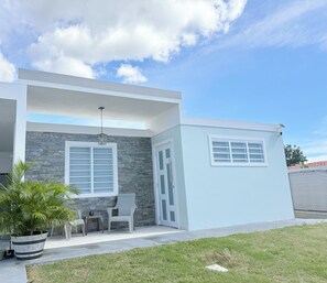 A modern house with a stone facade, a covered porch, and a small attached garage. - Sun Beach Escape – Vacation Rental in Boquerón, Cabo Rojo (Boquerón)