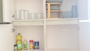 A kitchen cabinet with shelves containing glassware, plates, and condiment containers. - Sun Beach Escape – Vacation Rental in Boquerón, Cabo Rojo (Boquerón)