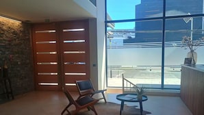 Eine moderne Lobby mit einem großen Glasfenster, einem Empfangstresen und zwei Holzstühlen.