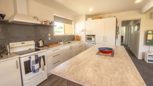 Une cuisine moderne avec des meubles blancs, un grand îlot central, un four à micro-ondes et une cuisinière.