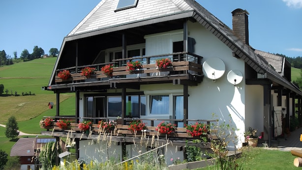 A two-story house with a balcony, a satellite dish, and a chimney.