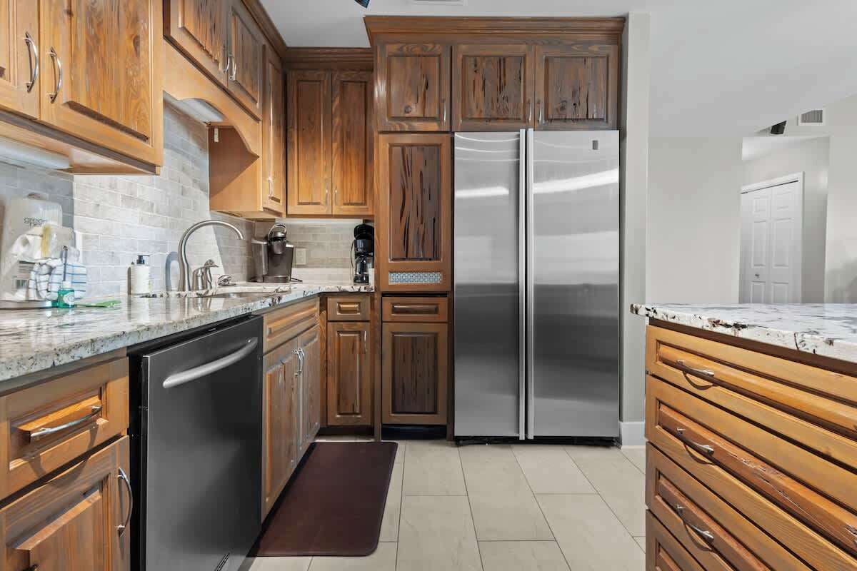 Une cuisine avec des meubles en bois, des appareils électroménagers en acier inoxydable et un plan de travail en marbre.