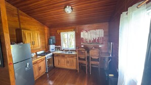Cocina de cabaña de madera con refrigerador, estufa, lavaplatos y armarios de madera.