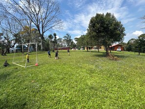Un espacio al aire libre con césped, un arco de fútbol, árboles y un edificio al fondo.