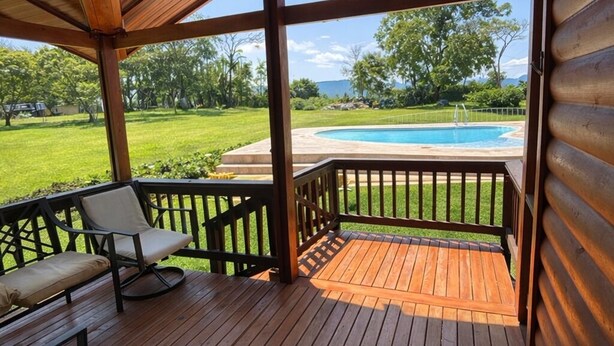 Una terraza de madera con una piscina al fondo.