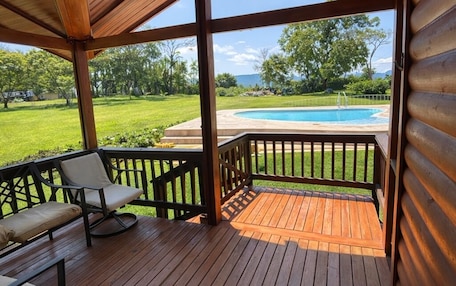 A wooden deck with a pool in the background.
