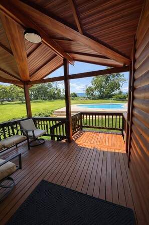 Una terraza de madera con una piscina al fondo.
