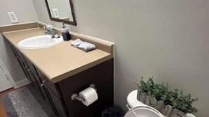 Et badeværelse med toilet, vask og spejl.
