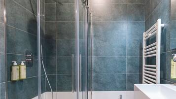 A modern bathroom with a glass-enclosed shower, a white sink, and a towel rack.