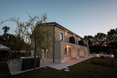 A modern two-story building with a balcony, outdoor seating, and a well-maintained lawn.