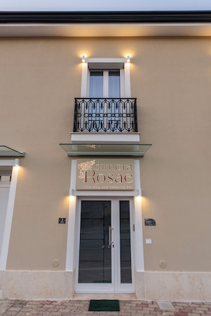 A building with a balcony, a sign reading 'Dimora Rosace,' and a door with a glass panel.. Dimora Rosae