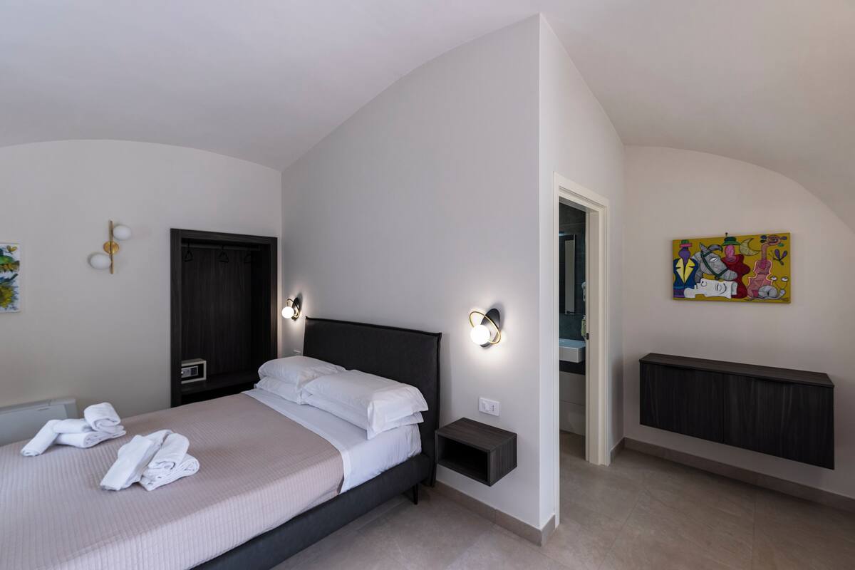 A bedroom with a bed, bedside tables, a door, and a radiator.