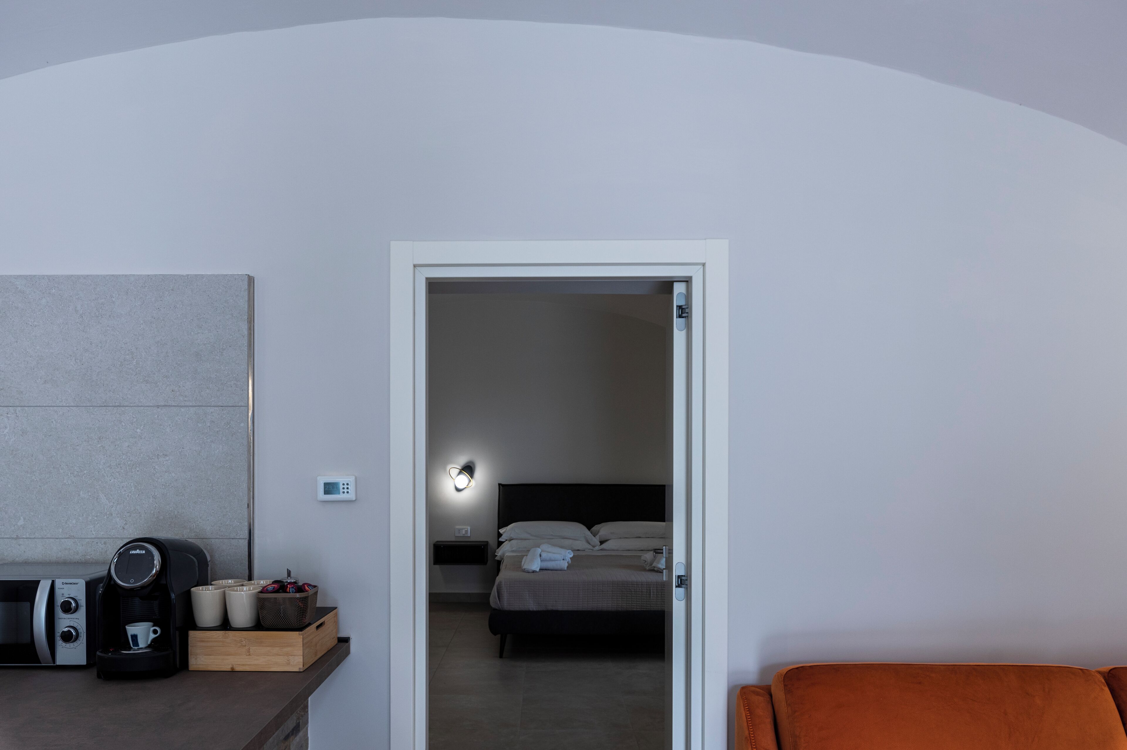 A hotel room with a bed, bedside table, and a coffee machine.