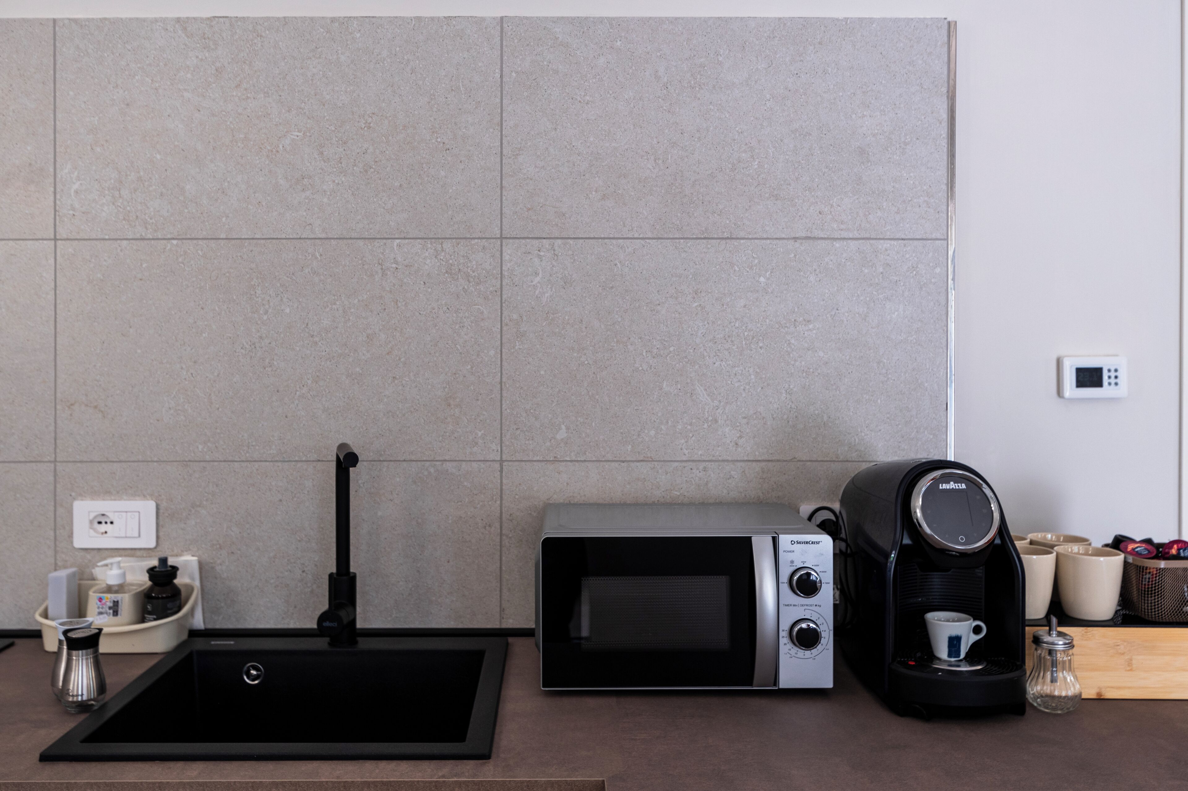 A kitchen with a sink, a coffee machine, and a microwave.
