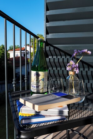 A metal table with a bottle, glasses, and books.