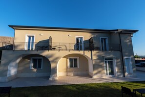 A two-story building with a balcony, arched windows, and a flat roof.