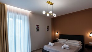 A hotel room with a bed, curtains, wall-mounted lights, and a ceiling light fixture.