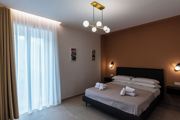 A hotel room with a bed, curtains, wall-mounted lights, and a ceiling light fixture.