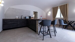 A modern kitchen with a central island, bar stools, and a dining table.
