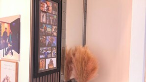 A room with a mirror, a framed collage of photos, and a vase with dried plants. - Room-room in Blackburn - Peters Place (Blackburn)