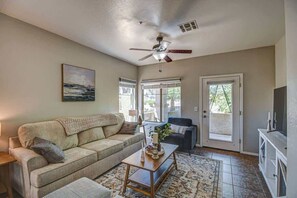 A living room with a beige sofa, a coffee table, a ceiling fan, and a painting on the wall. - Modern 2BR Condo w/ Pool & Parking in Scottsdale (Scottsdale)
