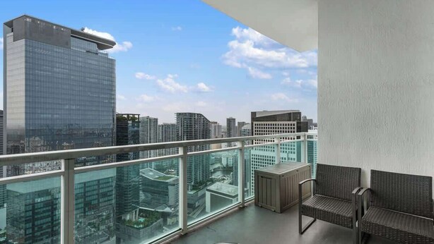 Un balcon avec vue sur la ville, un canapé en osier et une petite table.