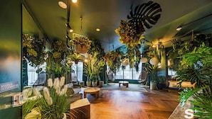 A spacious room with wooden flooring, multiple seating areas, and abundant indoor plants. - Chic Downtown Studio in Miami (Miami)
